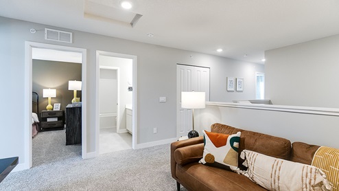 Upper level carpeted loft area with couch and television.