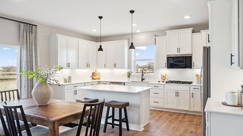 Kitchen with white cabinets, backsplash, and pendant lighting.