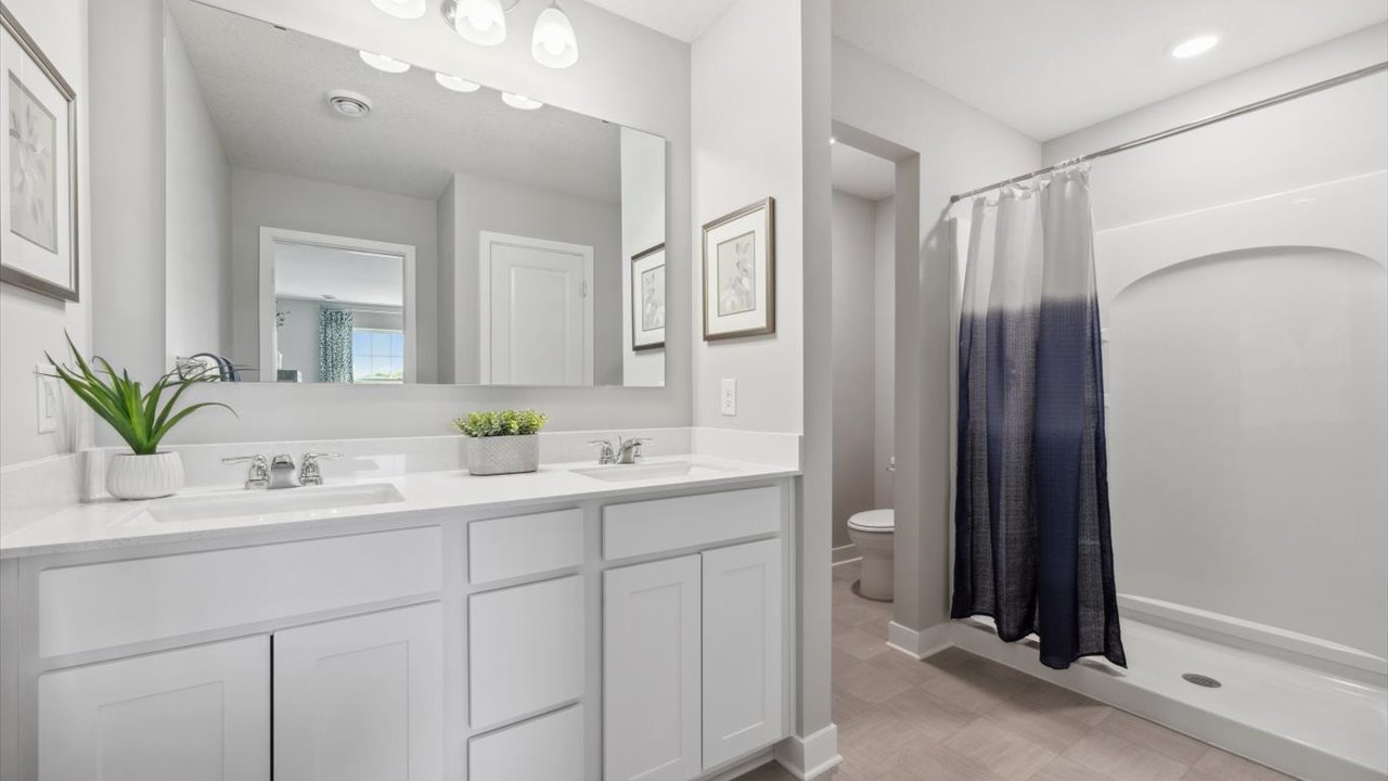 Private bathroom with white cabinets and quartz double vanity.