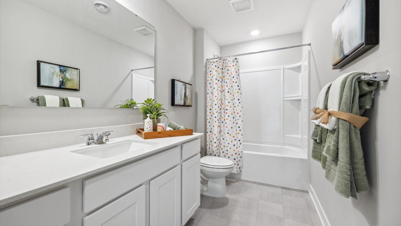 Secondary bathroom with quartz double vanity and white cabinets.