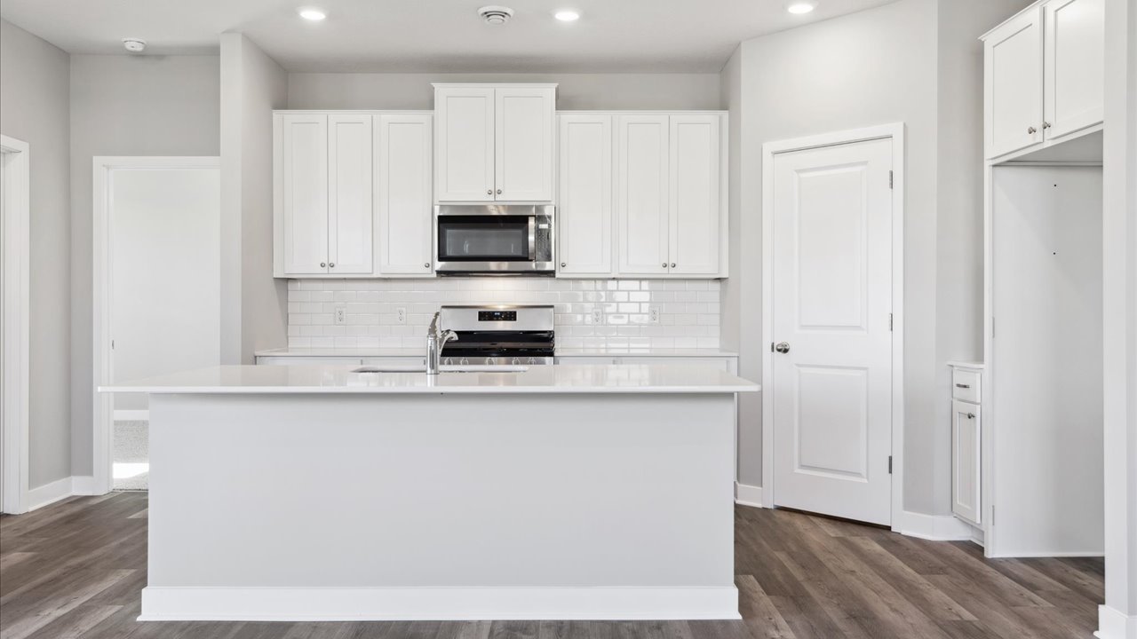 Straight on view of kitchen with four-person island with quartz countertops.