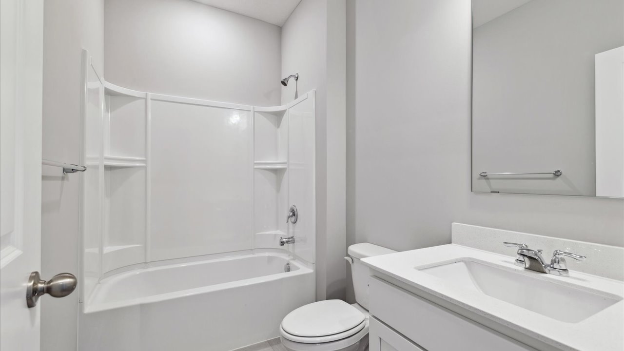 Secondary bathroom with white cabinets and quartz countertop.