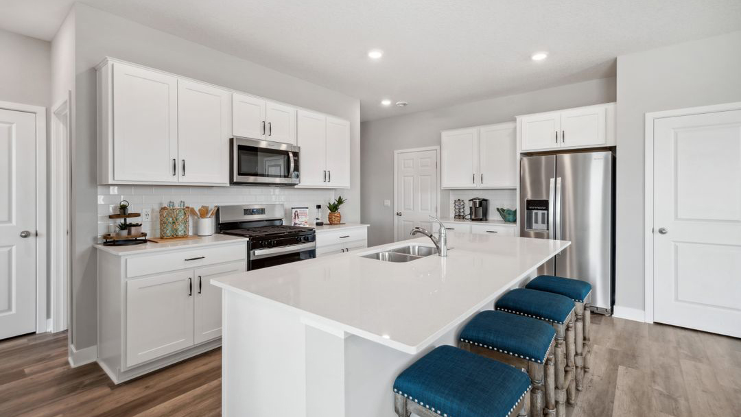 Angled view of kitchen with white cabinets and quartz countertops.