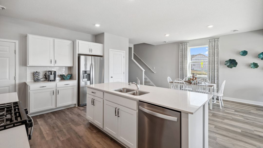 Kitchen island with white cabinets and stainless steel diswasher.