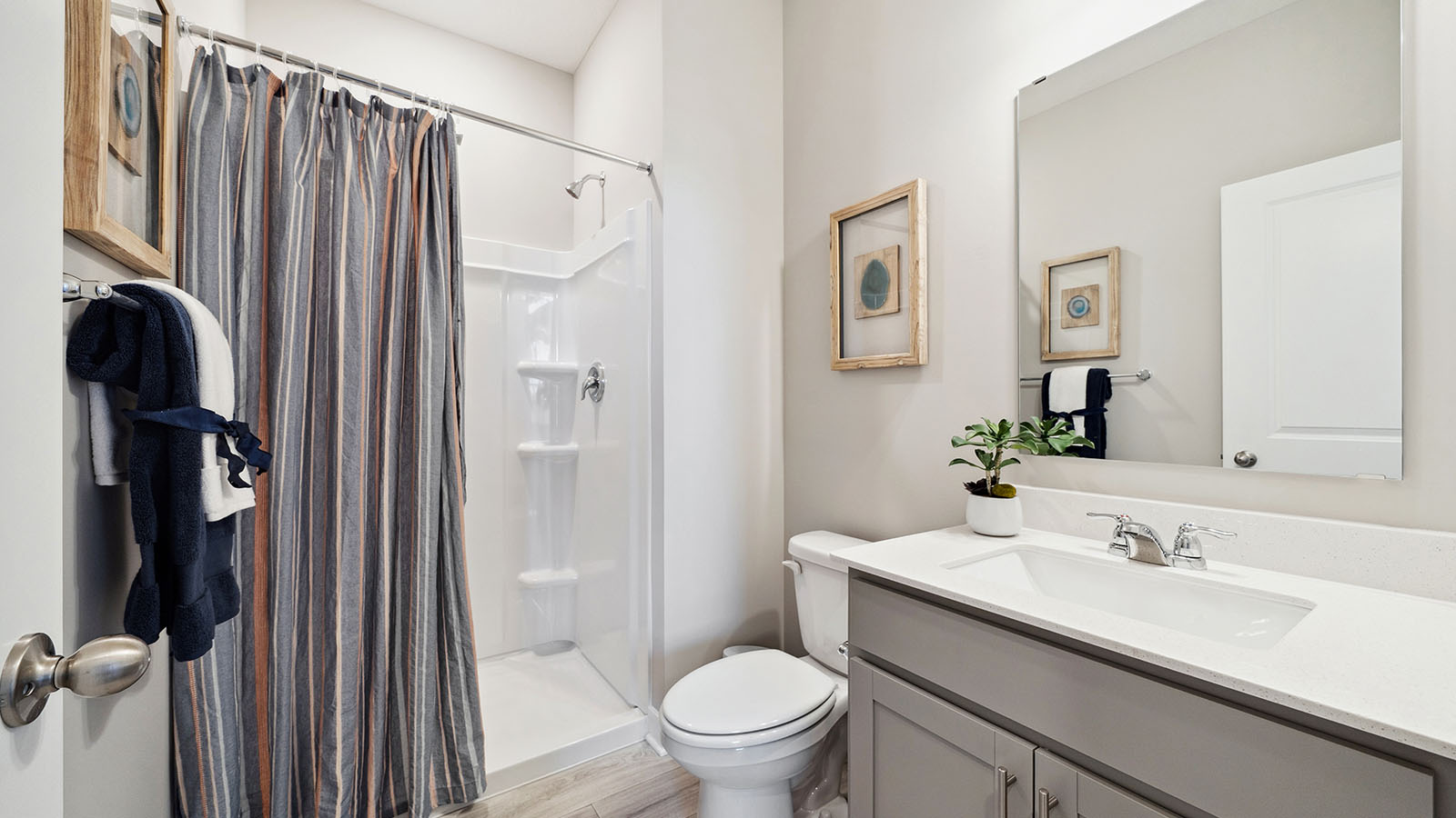 Main level bathroom with gray single sink vanity and quartz vanity countertop.