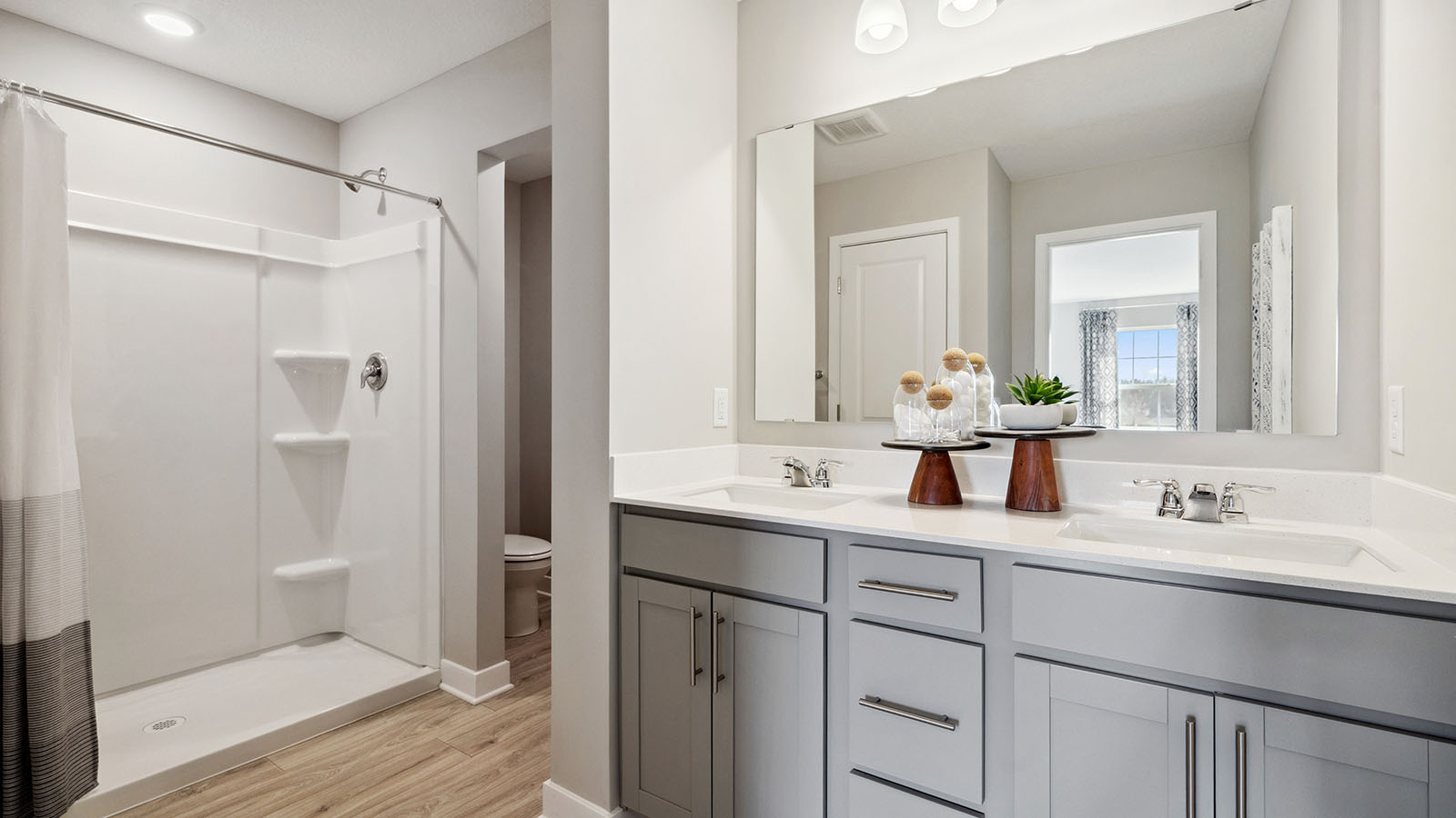 Private bathroom with gray double sink vanity and quartz vanity countertop.
