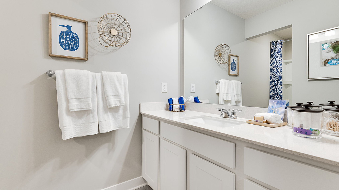 Secondary bathroom with quartz vanity countertop and white cabinets.