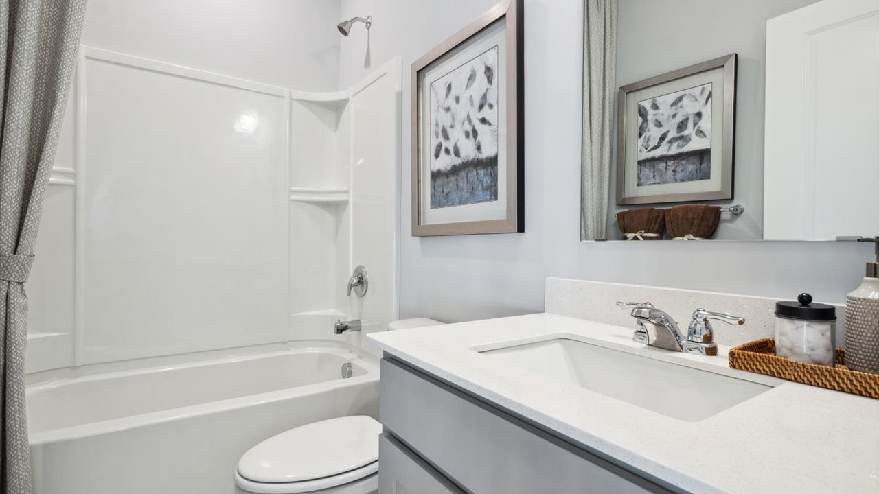 Main level bathroom with gray single sink vanity and quartz vanity countertop.