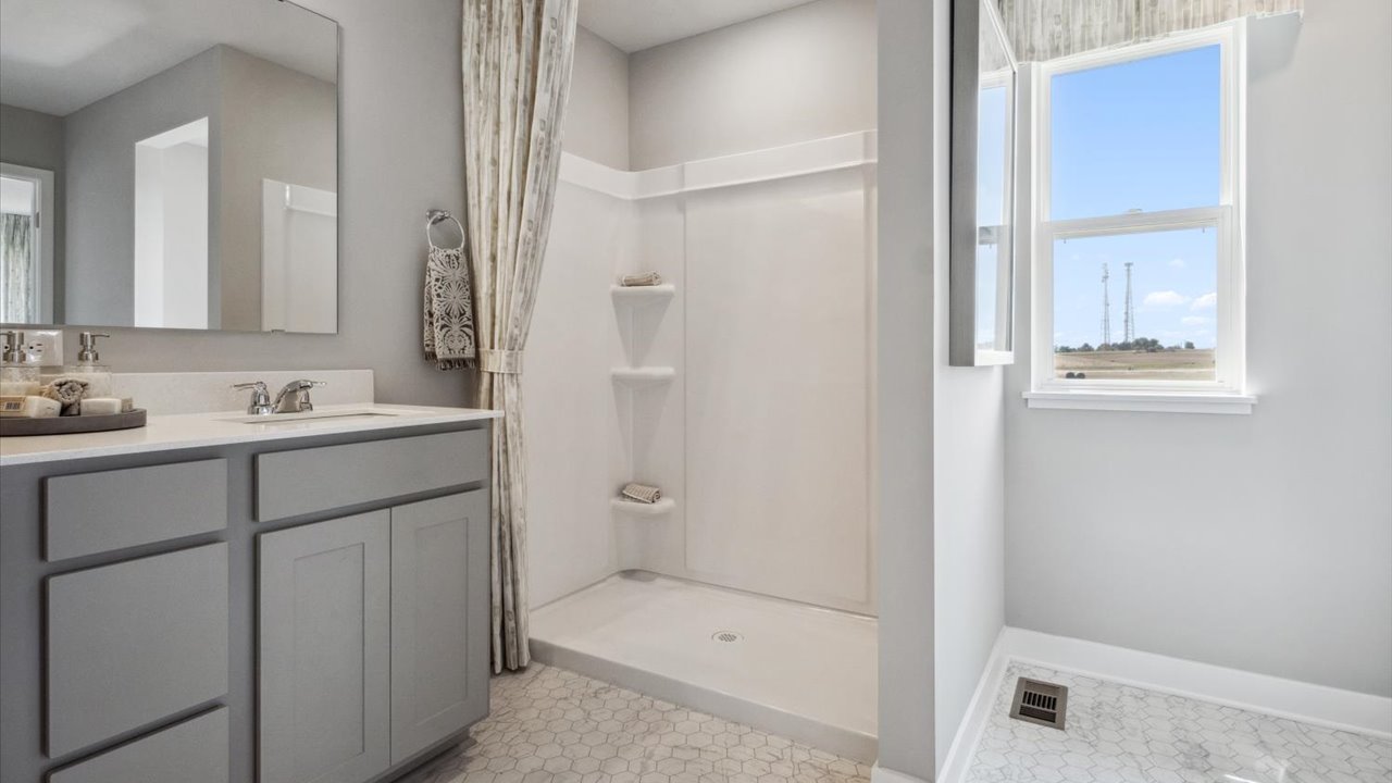 Private bathroom with gray cabinets and quartz double vanity.