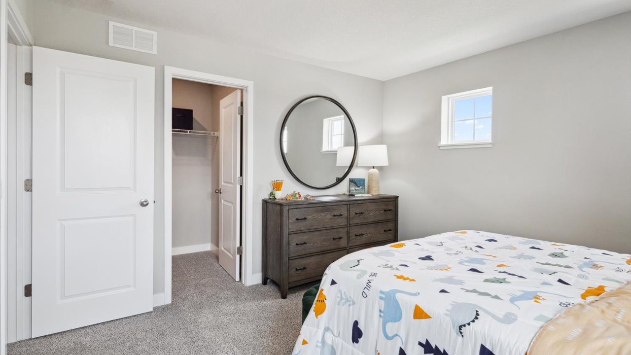 Carpeted secondary bedroom with walk-in closet.