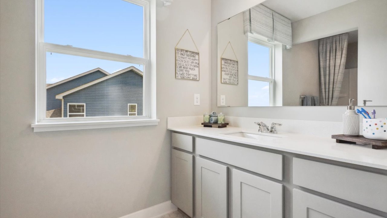 Secondary bathroom with gray cabinets and quartz vanity countertop.
