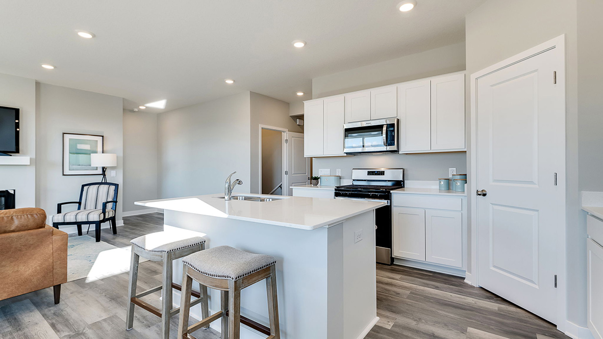 Angled view of kitchen with white cabinets and corner pantry.