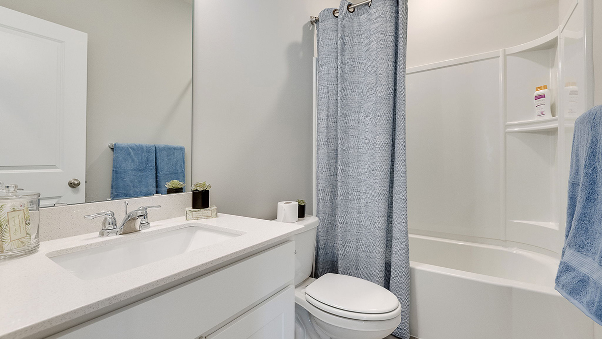 Secondary bathroom with white single sink vanity and quartz vanity countertop.