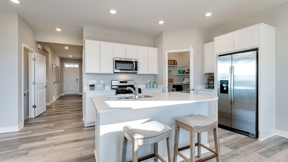 Angled view of kitchen with white cabinets and corner pantry.