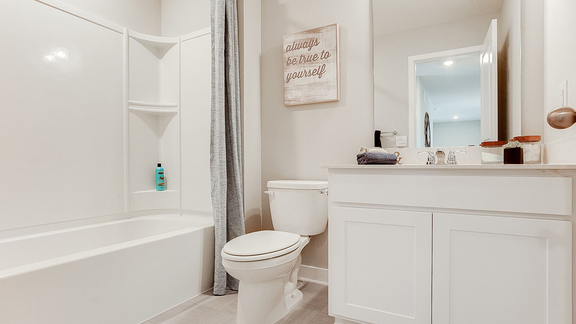 Secondary bathroom with quartz vanity and white cabinets.