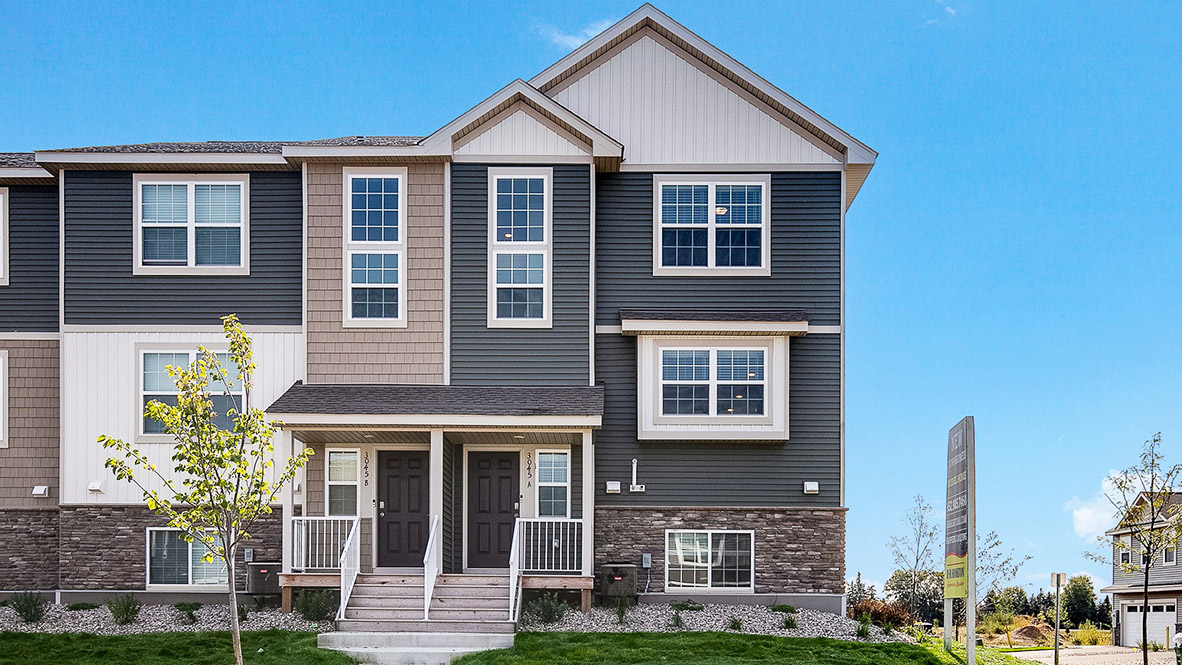 front exterior of a townhome with grey siding and stone accents