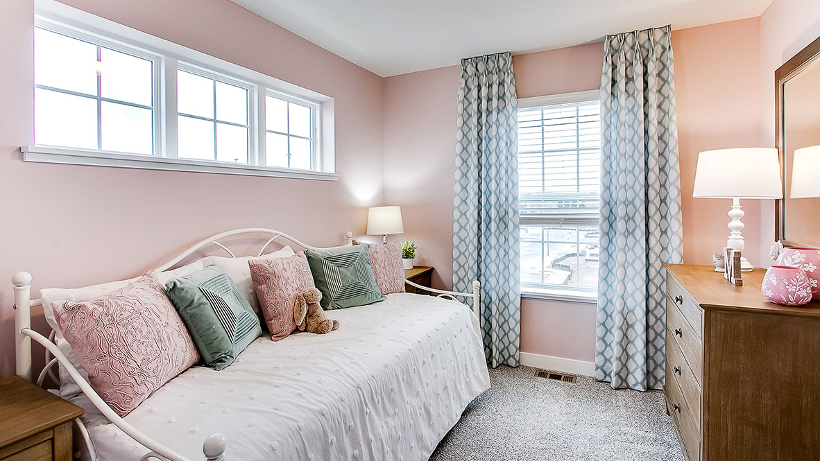 bedroom with beige carpet, pink walls and a window