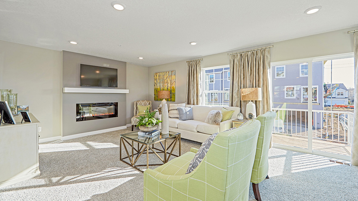 Carpeted living room with electric fireplace.