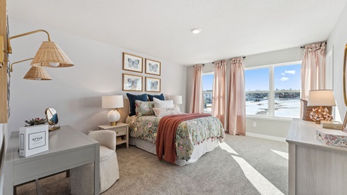 bedroom with three windows, a bed, desk, and dresser