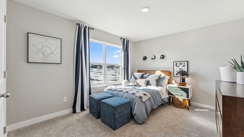 bedroom with a bed pushed against the large window with a brown dresser