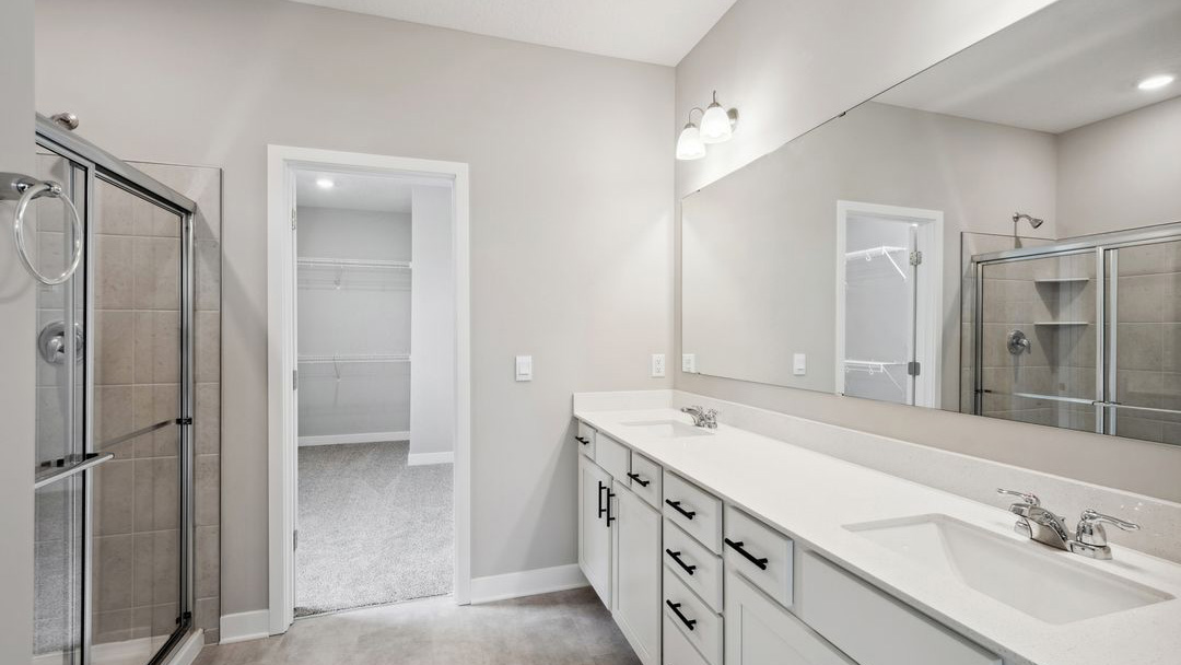 bathroom with dual vanity sinks, toilet, and a walk in shower