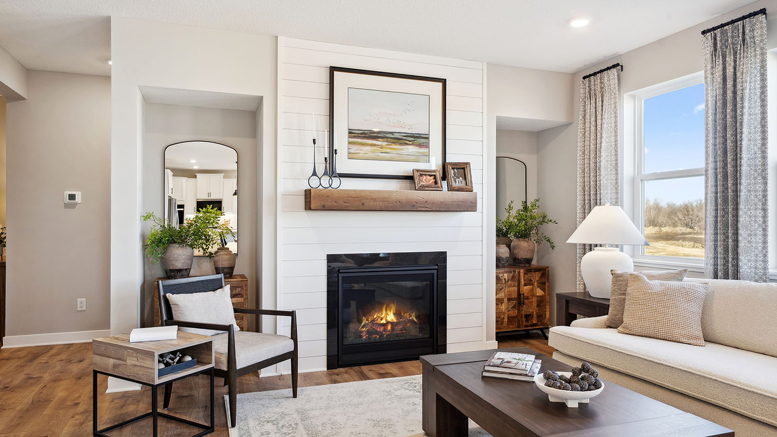 Spacious living room with brown flooring, white walls, a black fireplace and windows