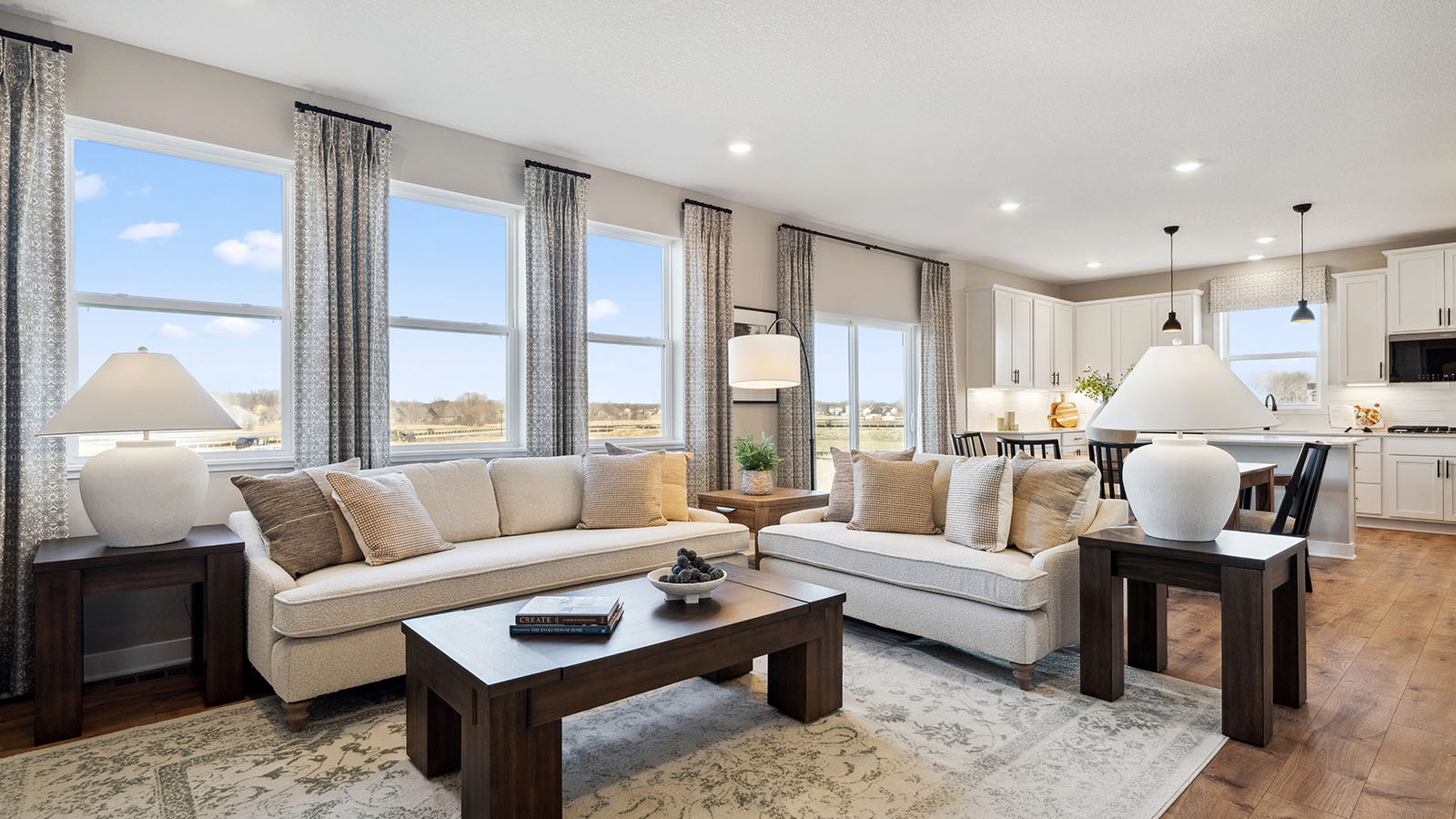 Spacious living room with brown flooring, white walls, a black fireplace and windows