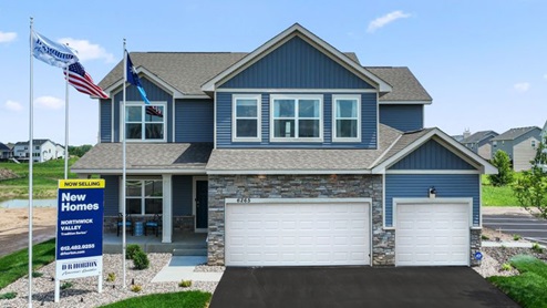 front exterior of a two story home with blue siding, stone accents and a three car garage