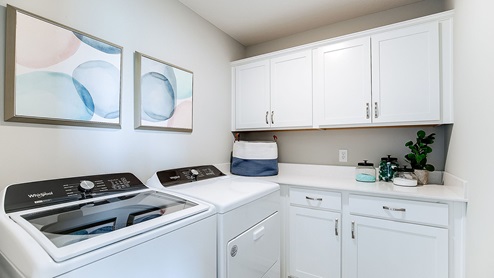 Upper level laundry room near the bedrooms with white cabinetry.