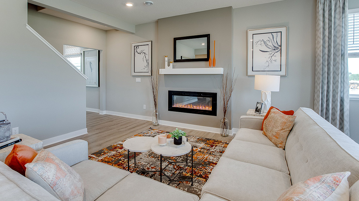 Spacious living room with brown flooring, white walls, a black fireplace and windows