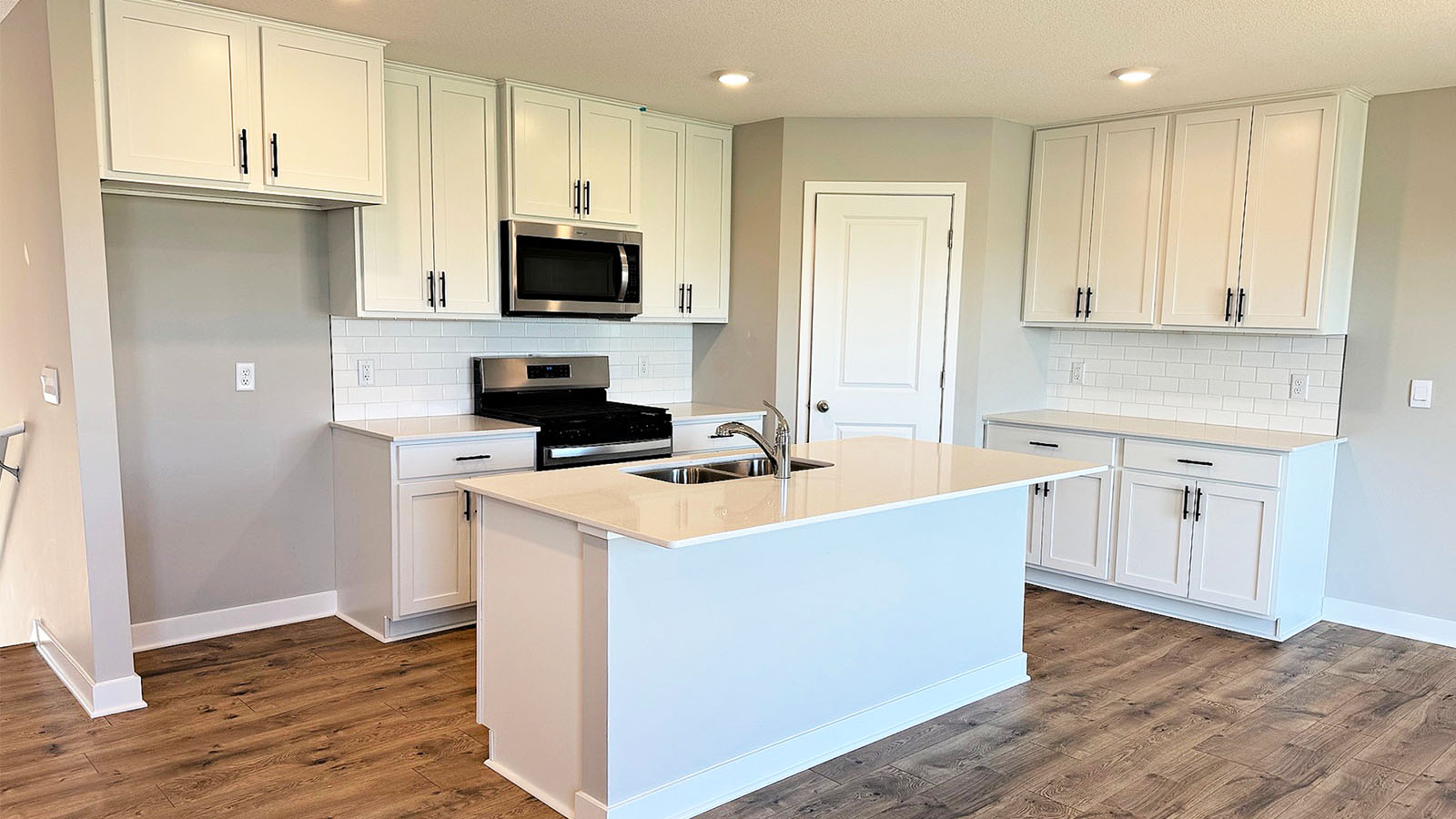 Angled view of kitchen with white cabinetry and quartz countertops