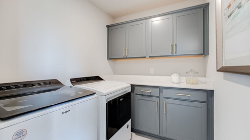 Upper level laundry shown with cabinets.