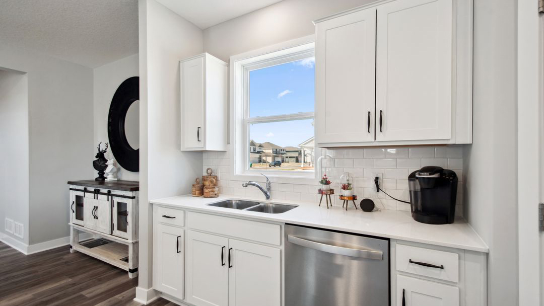 Angled view of kitchen with white cabinets and quartz countertops.