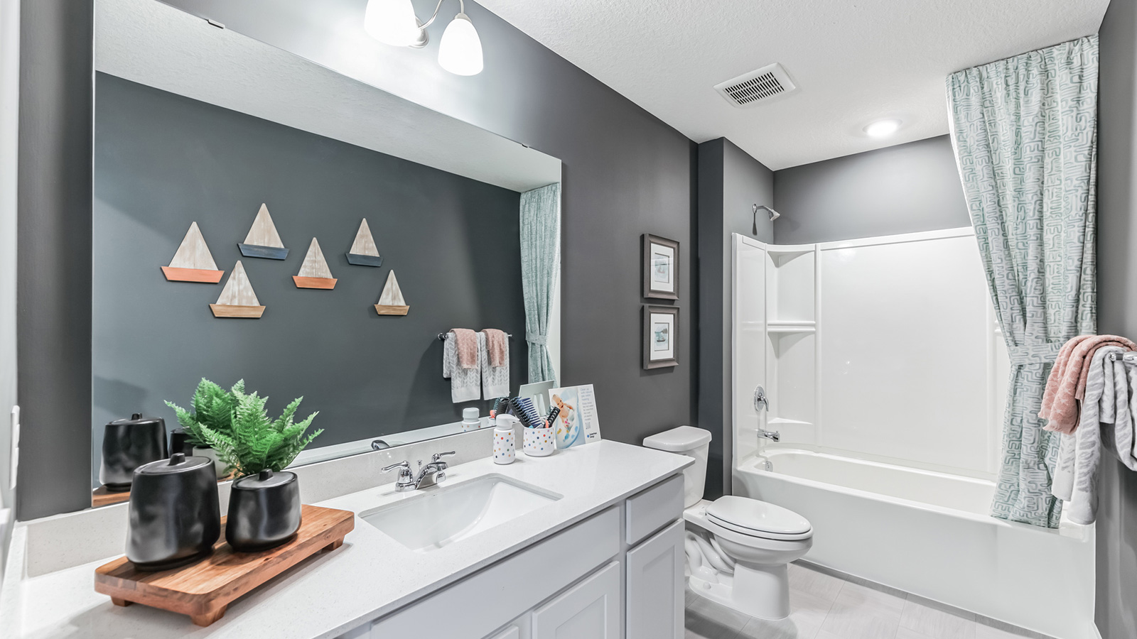 Secondary bathroom with quartz vanity countertop and white single sink vanity.