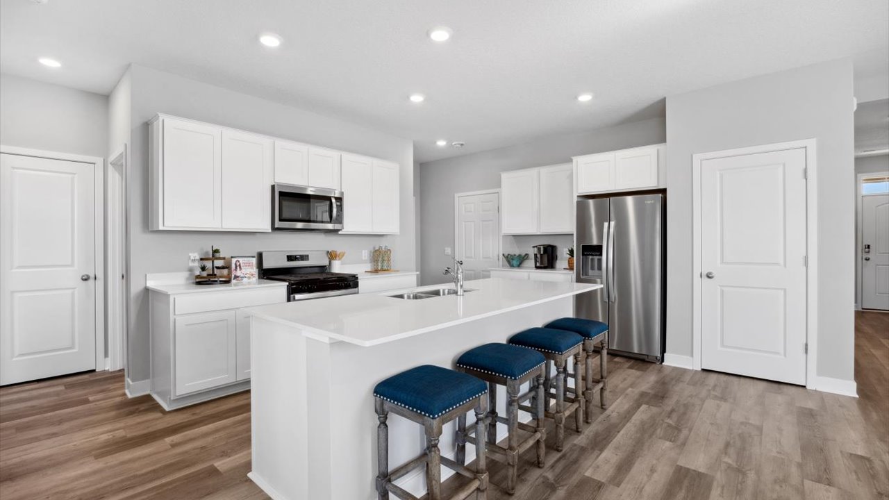 Angled view of kitchen with white cabinets and quartz countertops.