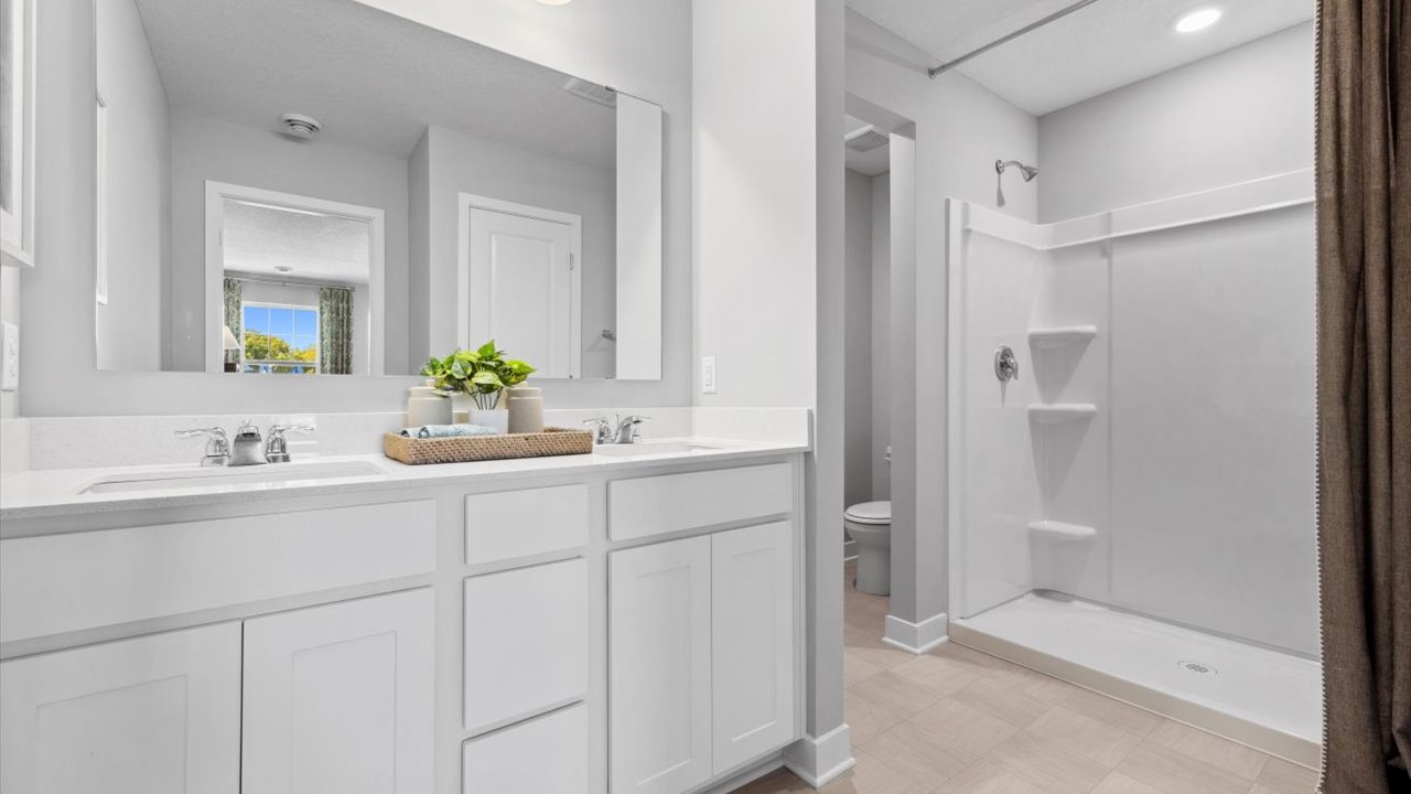 Private bathroom with white double sink vanity and quartz  vanity countertop.