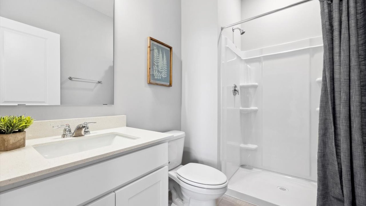 Main level bathroom with white cabinets and quartz double vanity.