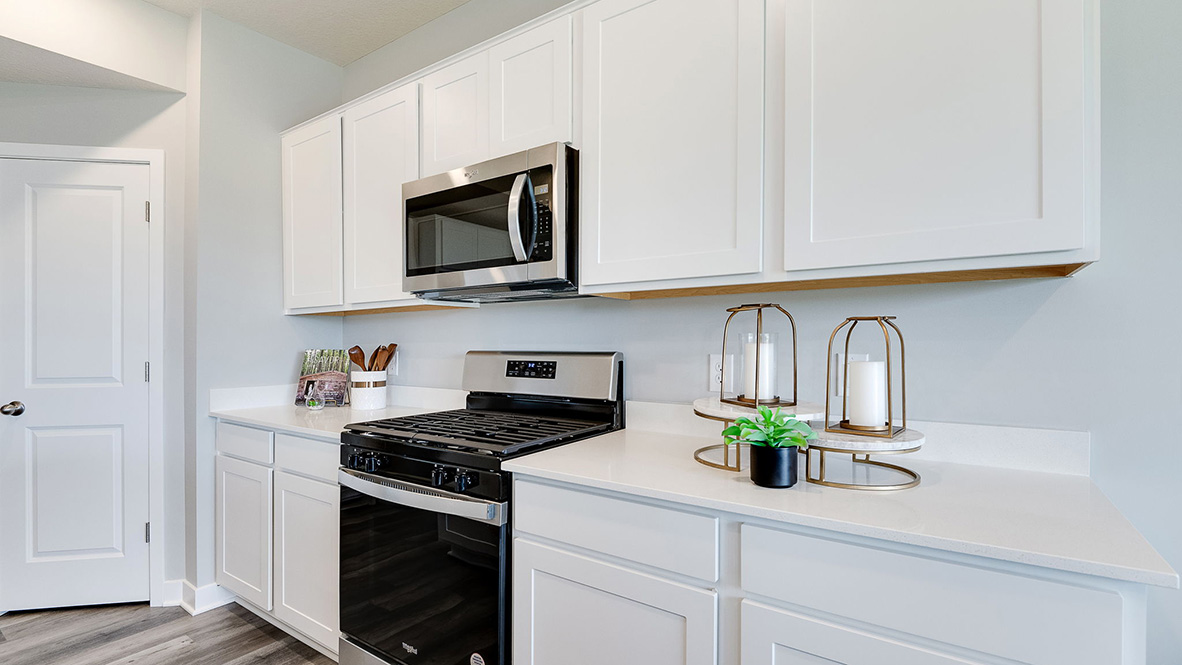 Kitchen with white cabinets and stainless steel oven and microwave.