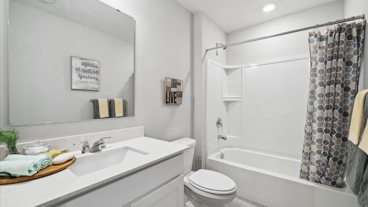 Secondary bathroom with white cabinets and quartz countertop.