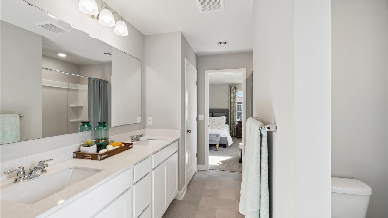 Private bathroom with white cabinets and quartz double vanity.
