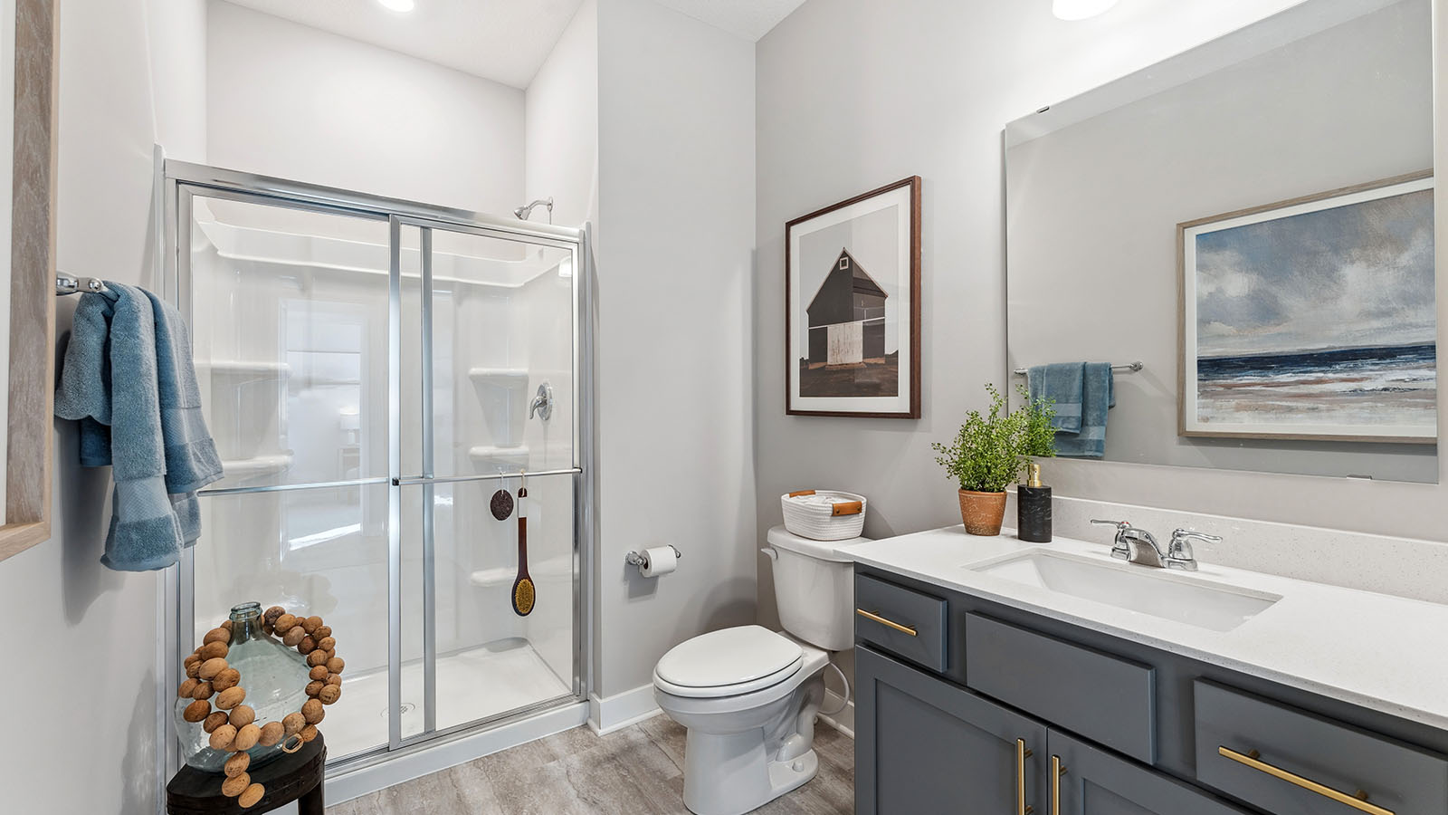Main level bathroom with shower, toilet, and vanity with harbor gray cabinets and quartz countertop