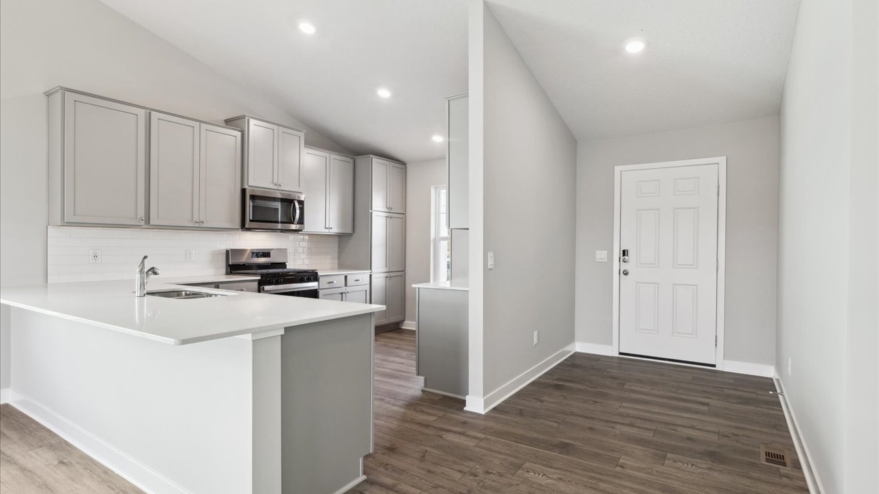 View from kitchen to dining and living areas near outdoor access Ravine Crossing By D.R. Horton