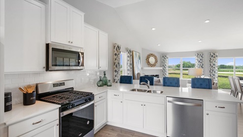 Spacious kitchen with white cabinets and stainless appliances.