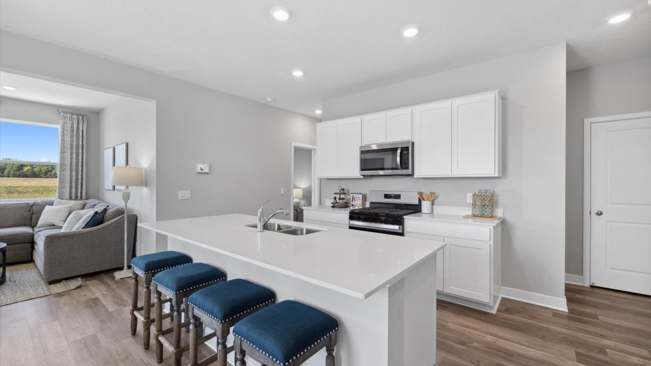Angled view of kitchen with white cabinets and quartz countertops.