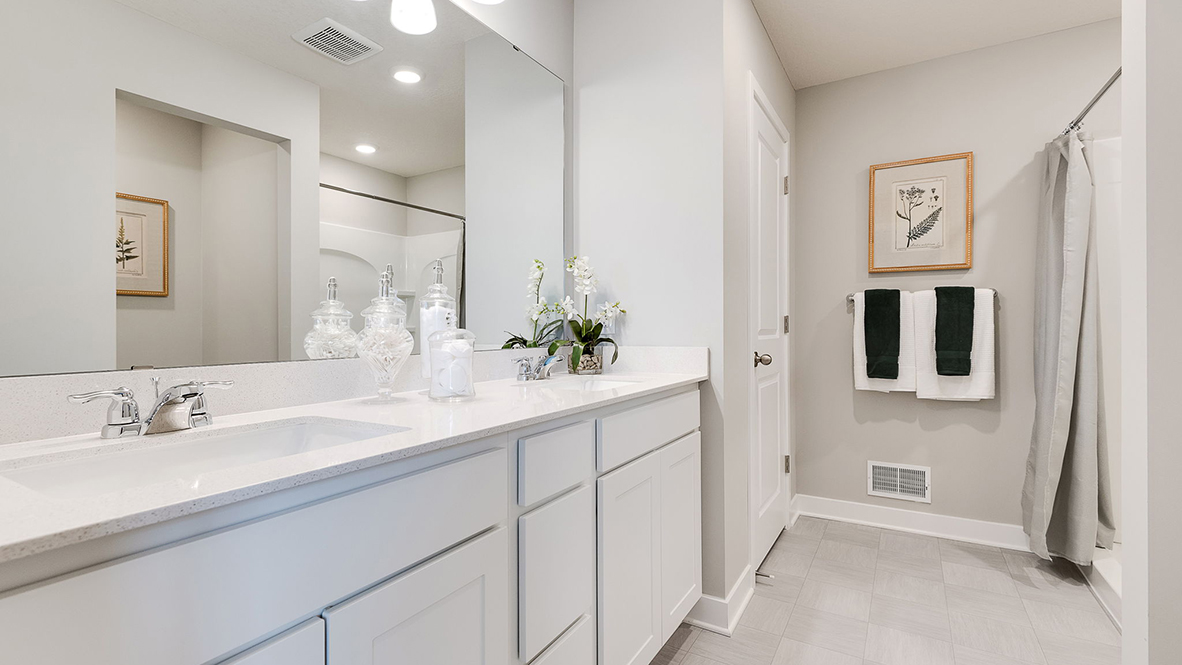 Private bathroom with white double sink vanity and quartz countertops.