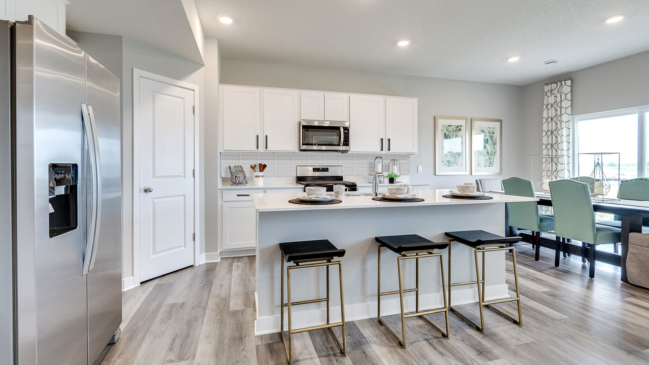 Angled view of kitchen with white cabinets and quartz countertops.