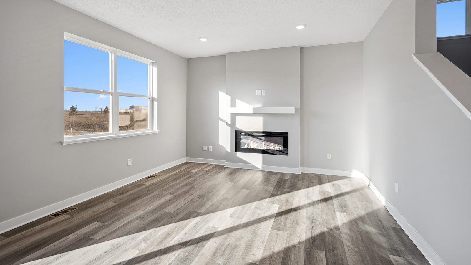Living room in this new home features a gas or electric fire place,  natural light, with fresh open concept Harvest View