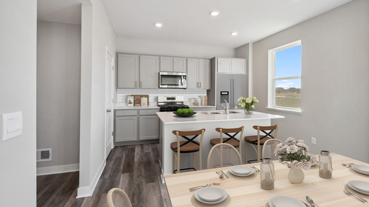 View from dining area to central kitchen island with pantry, cabinets, appliance suite included