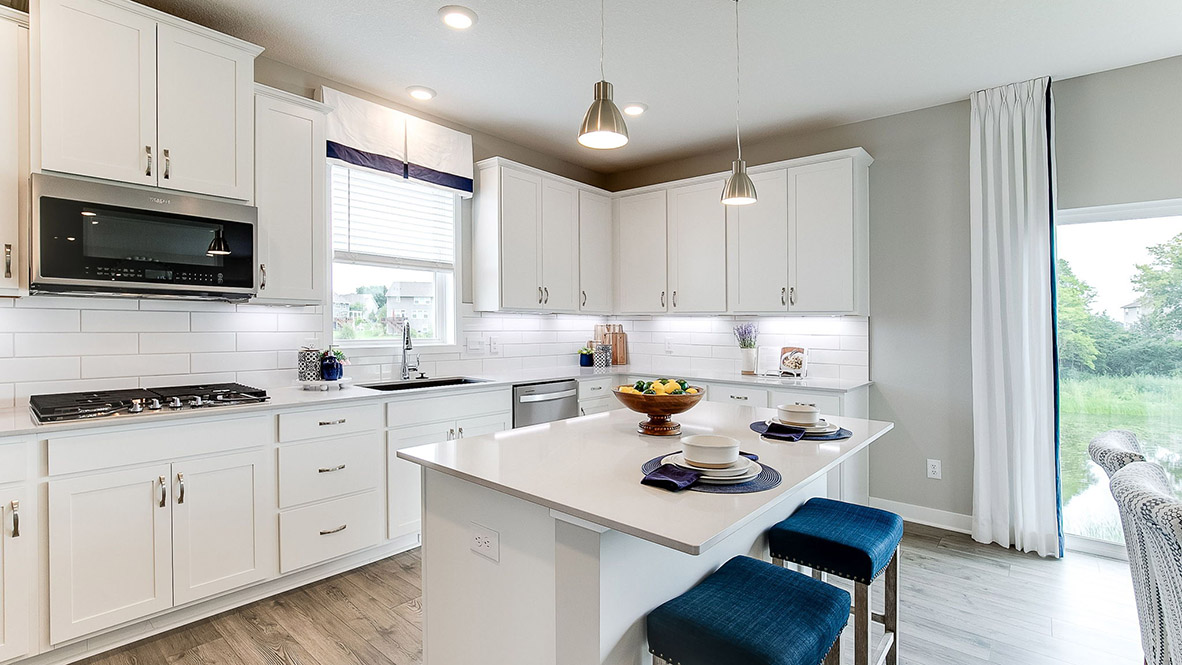 Kitchen with white cabinets, backsplash, and pendant lighting.