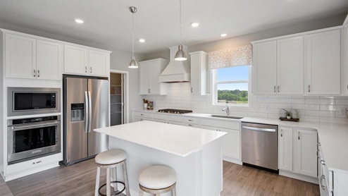 Kitchen with white cabinets, backsplash, and pendant lighting.